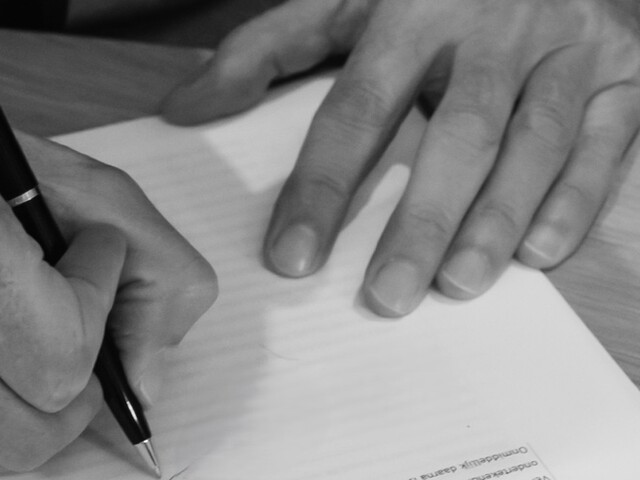 Hands signing a document