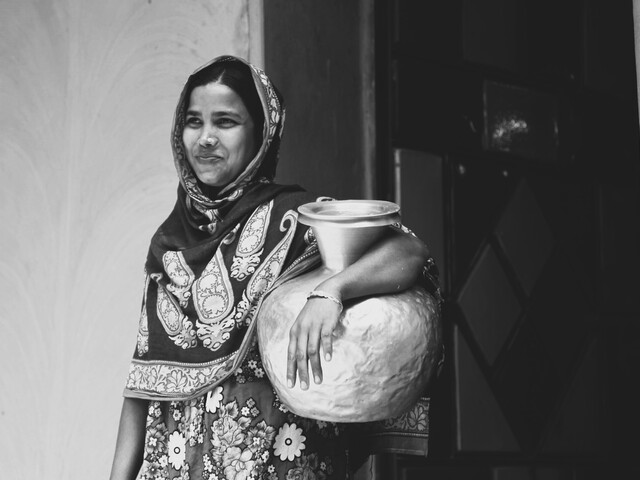 Young woman in front of her house with water container Bangladesh