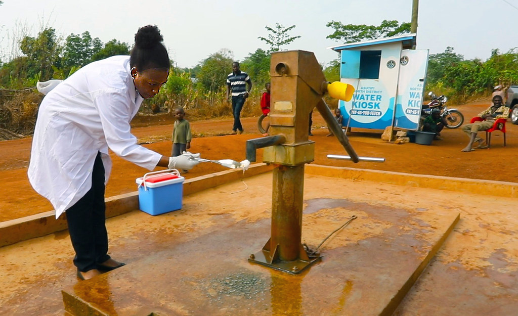 Janet Atebiya purifying the mouth of the pump at Kenyasi, before testing the water for E. coli