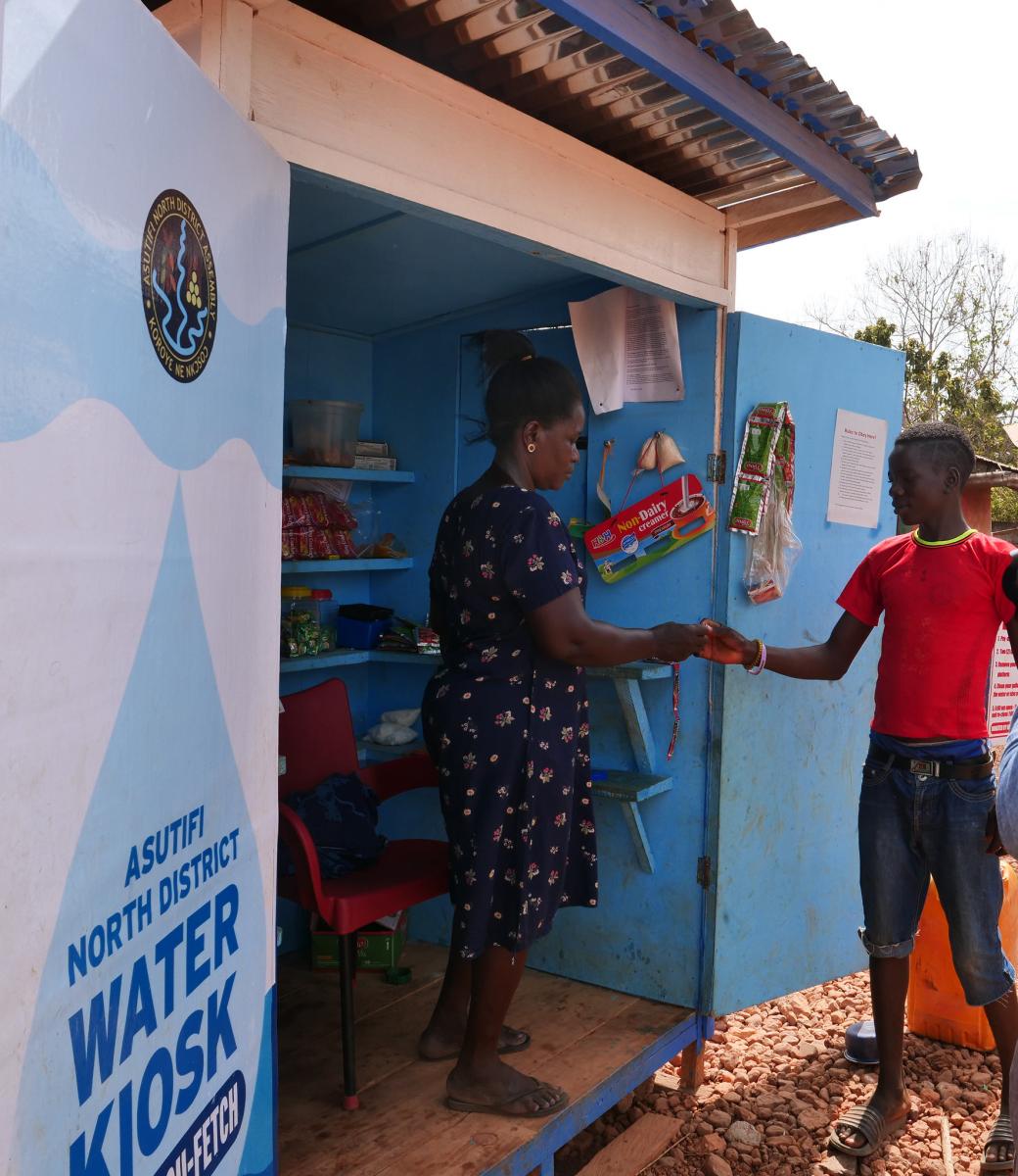 Doris Bosompimaah sells a razor blade to a young man in Panaaba village, Asutifi North