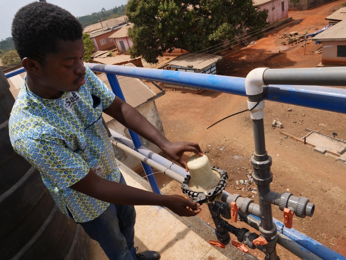 Martin Agyepong Safe Water Network field services officer checks a filter on the water tower at Wamahinso Martin Agyepong Safe Water Network field services officer checks a filter on the water tower at Wamahinso