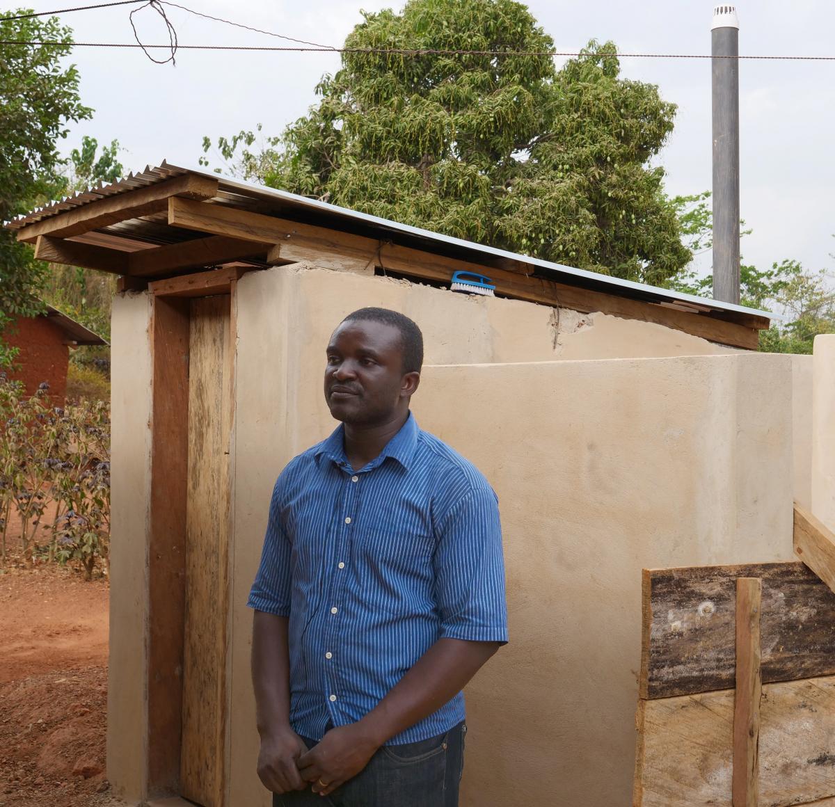 Festus Baudi, World Vision, outside the chief's household toilet in Panaaba Festus Baudi, World Vision, outside the chief's household toilet in Panaaba