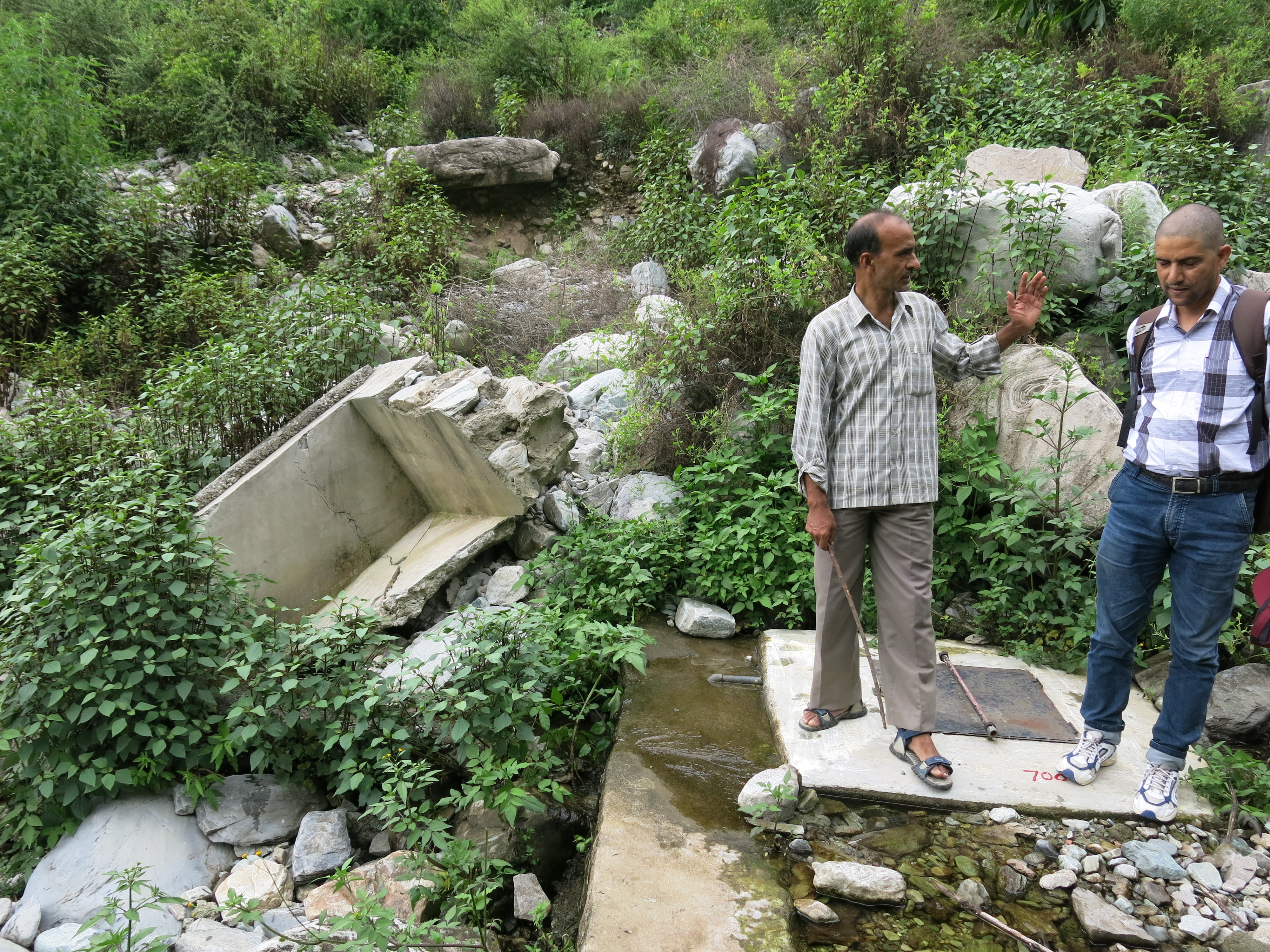 Photo 2: Inspecting the new intake structure of Kinsu; the remains of the old one that was washed away are visible on the left side of the photo