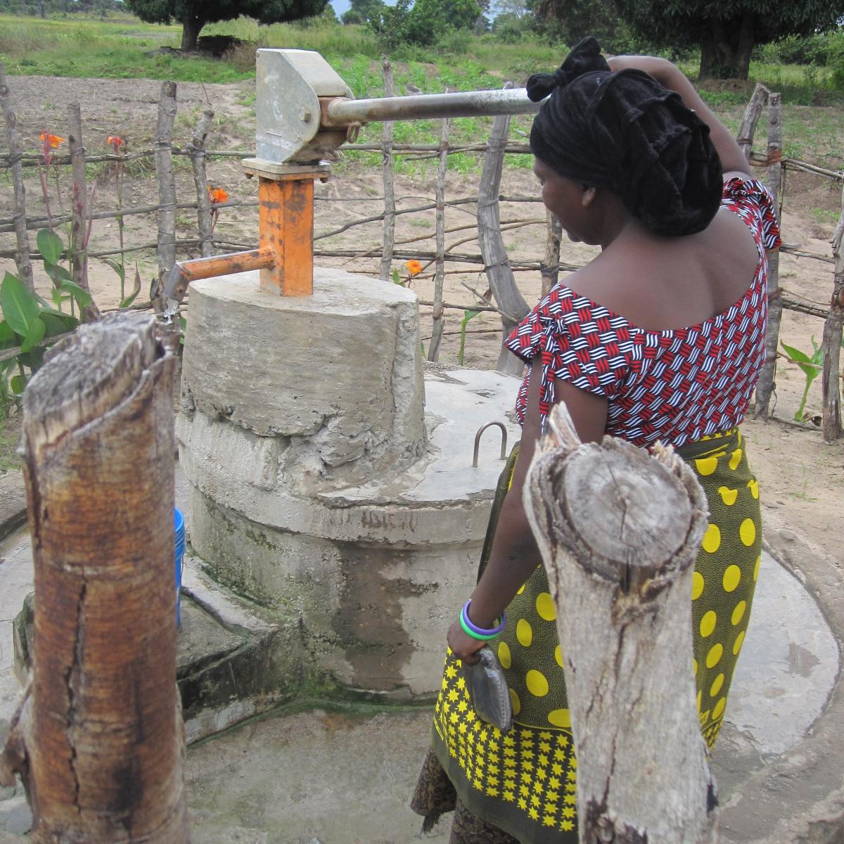 Woman using a rural water pump Woman using a rural water pump