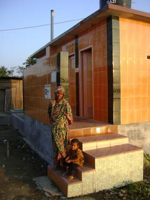 Arjina Khatun, the latrine caretaker, and her granddaughter Naher next to the male entrance to the latrine